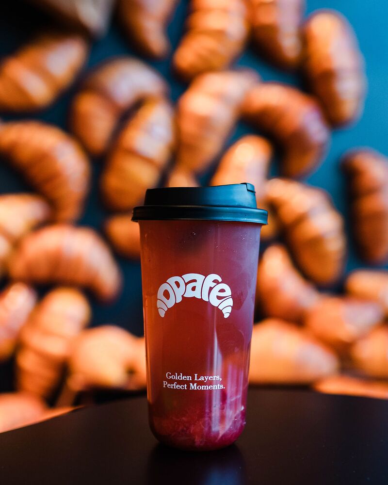 Berry fruit tea in an Opafe cup in front of the croissant wall