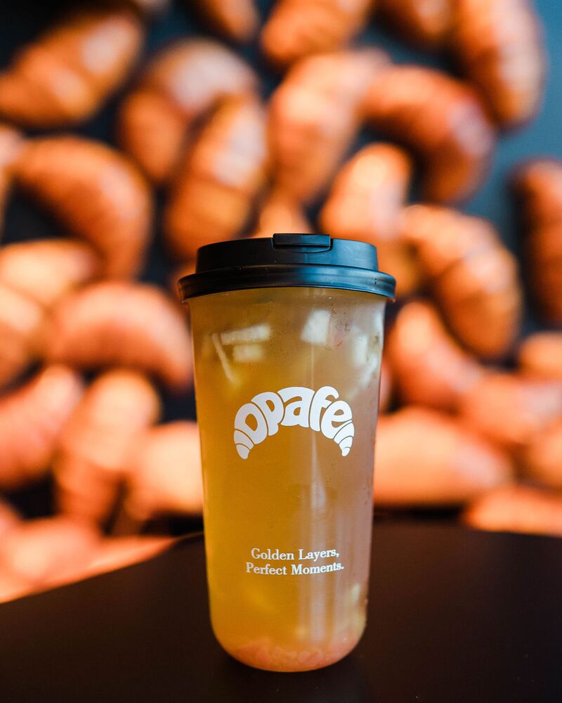 Fresh-fruit tea in an Opafe cup in front of the croissant wall