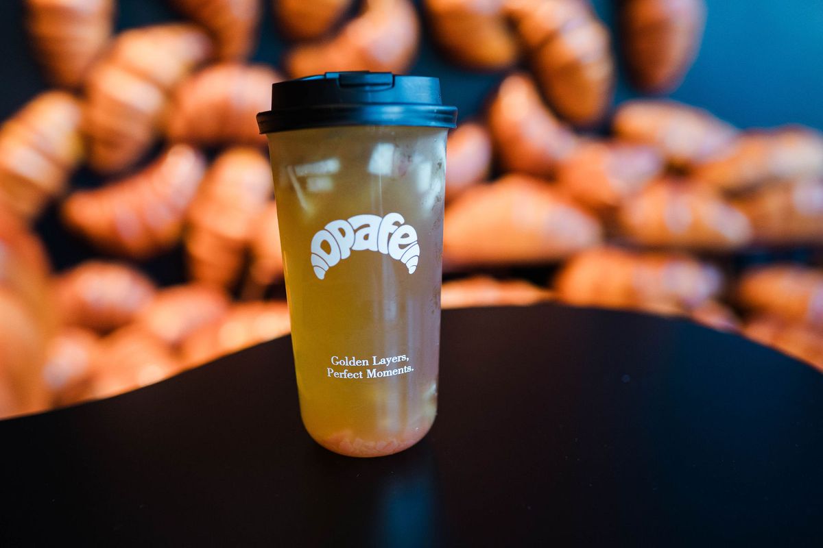 Fresh-fruit tea in an Opafe cup in front of the croissant wall